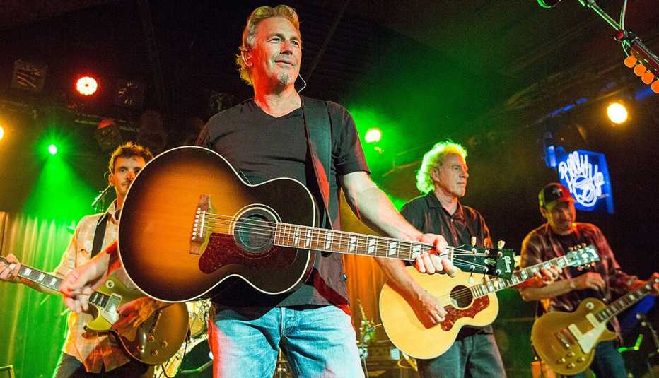 kevin costner on stage with a guitar and his band modern west