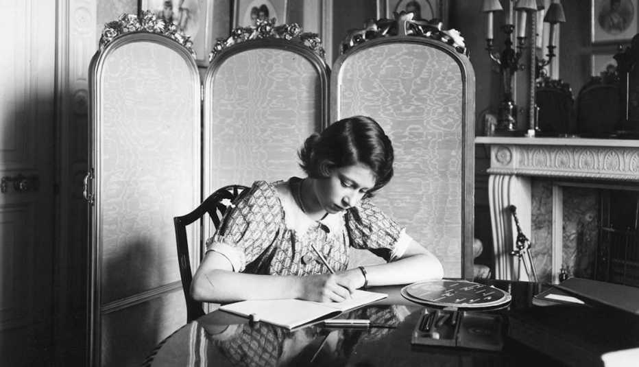 Princess Elizabeth writing in a notebook at a desk in Windsor Castle