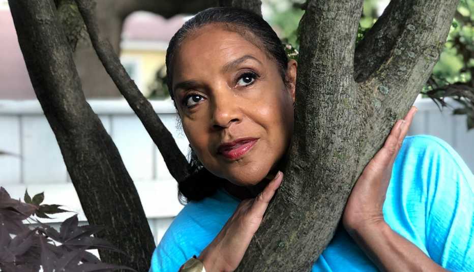 Actress Phylicia Rashad leans on a tree posing for photo