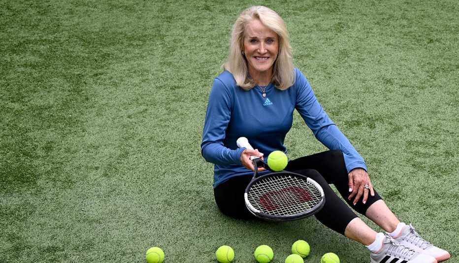 Tracy Austin seated on grass while bouncing a tennis ball on her racket