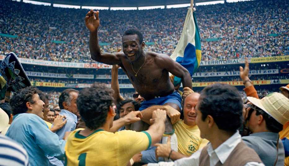 A shirtless Pele is lifted on the shoulders of his teammates after Brazil won the World Cup final in 1970