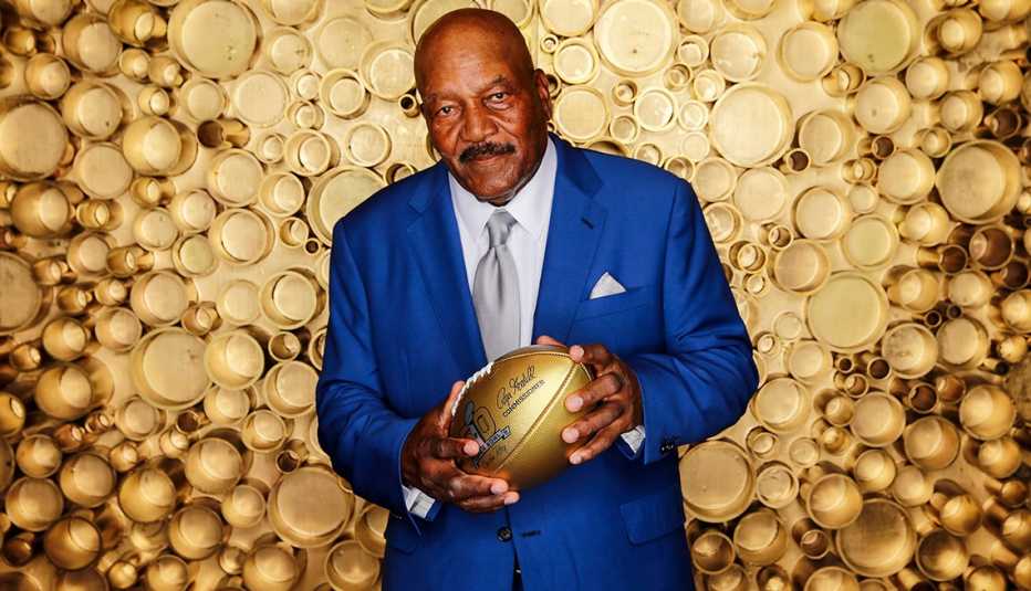 Football Hall of Fame running back Jim Brown holding a gold football at the NFL Honors awards show