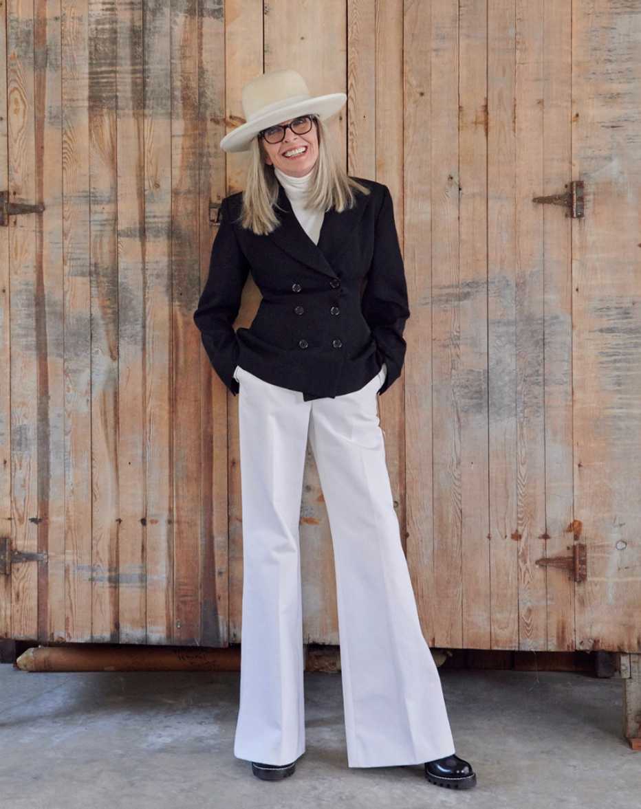 Diane Keaton looking sharp in white hat and turtleneck, black blazer, and white dress slacks