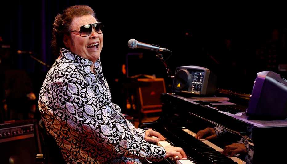 Ronnie Milsap sitting in front of a piano on stage at The Ryman Auditorium in Nashville, Tennessee
