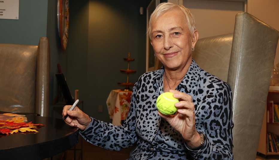 martina navratilova signs a tennis ball at the american cancer society hope lodge event