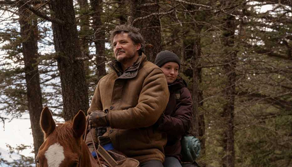 pedro pascal and bella ramsey riding a horse in a scene from the hbo series the last of us