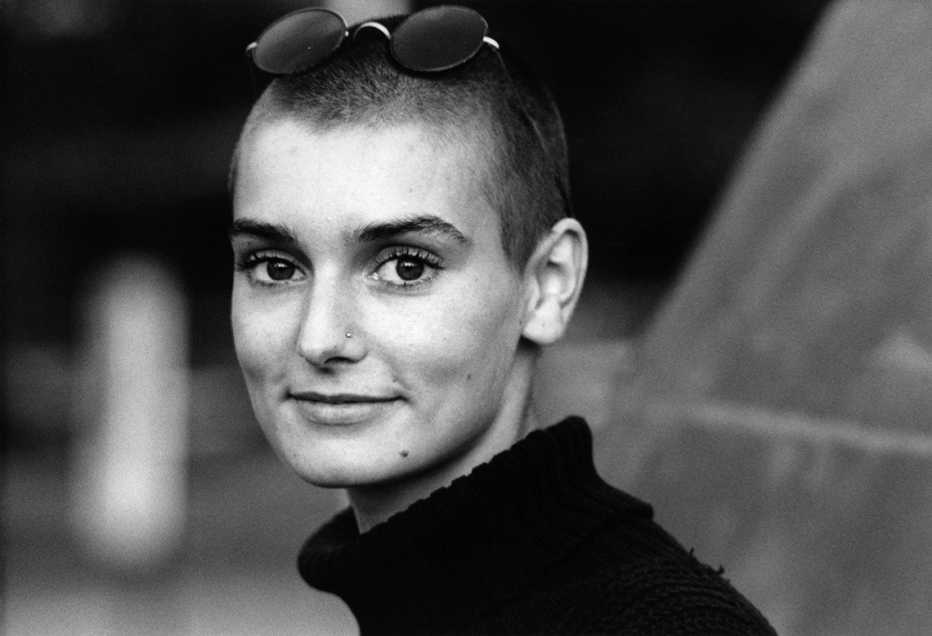 sinead o'connor smiling in a black and white portrait in 1990