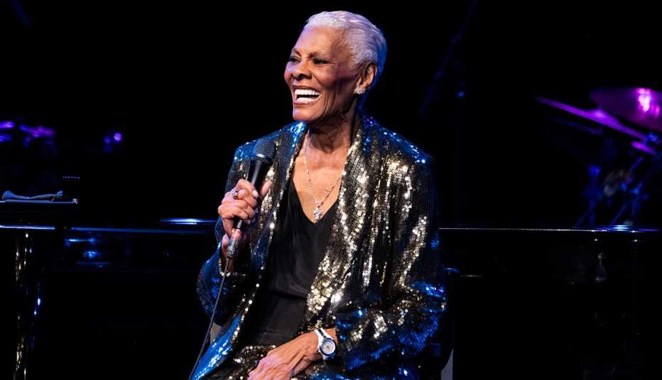 Singer Dionne Warwick smiles as she holds a microphone onstage while performing at City National Grove of Anaheim
