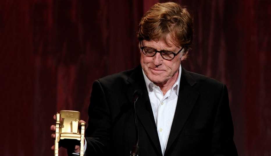 Robert Redford looks down at his Movies for Grownups Award