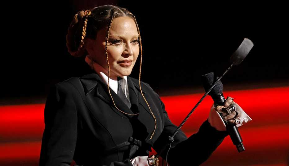 Madonna holding a microphone onstage as she presents an award at the 65th Grammy Awards