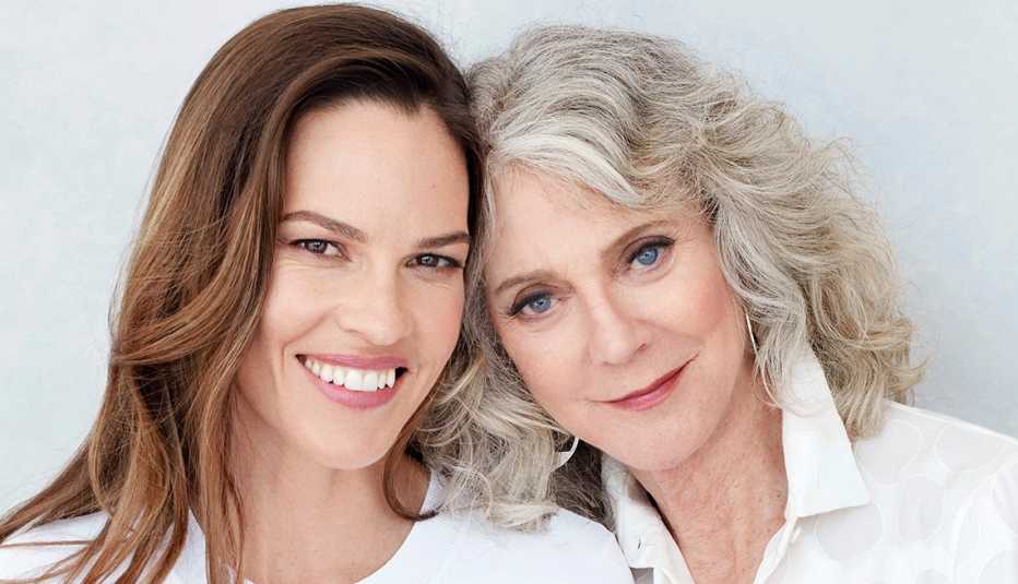 Hilary Swank and Blythe Danner smiling with their heads touching.