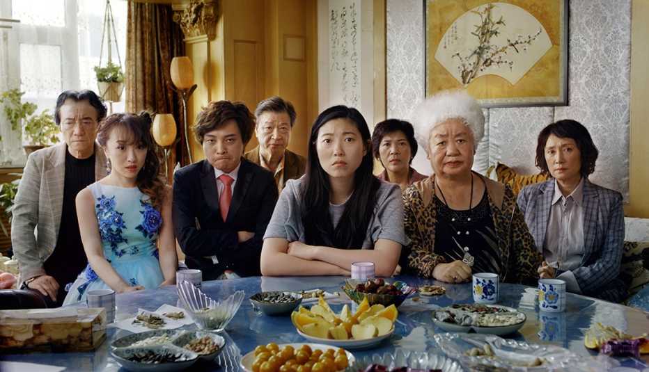 The cast of The Farewell seated in front of a table filled with food