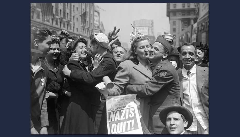 crowded street of returning soldiers and others embracing at the announcement of nazi defeat