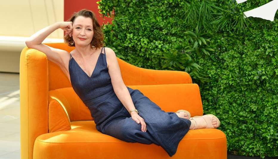 actress leslie manville reclines on an orange chair