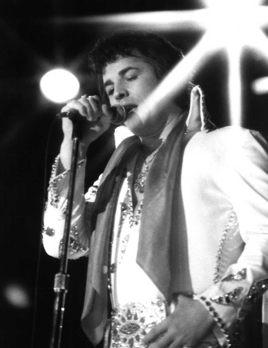 Don Johnson sings into a microphone while performing as Elvis Presley in Elvis and the Beauty Queen