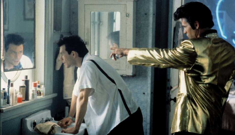Christian Slater looks into a mirror while Val Kilmer points at Slater from behind in a scene from True Romance