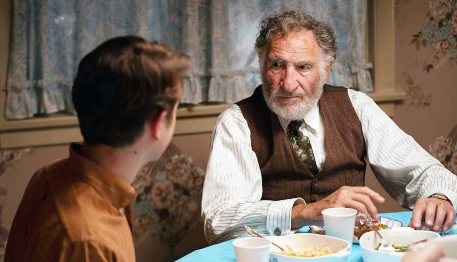 Judd Hirsch sitting at a dinner table talking to Gabriel LaBelle in the film The Fabelmans