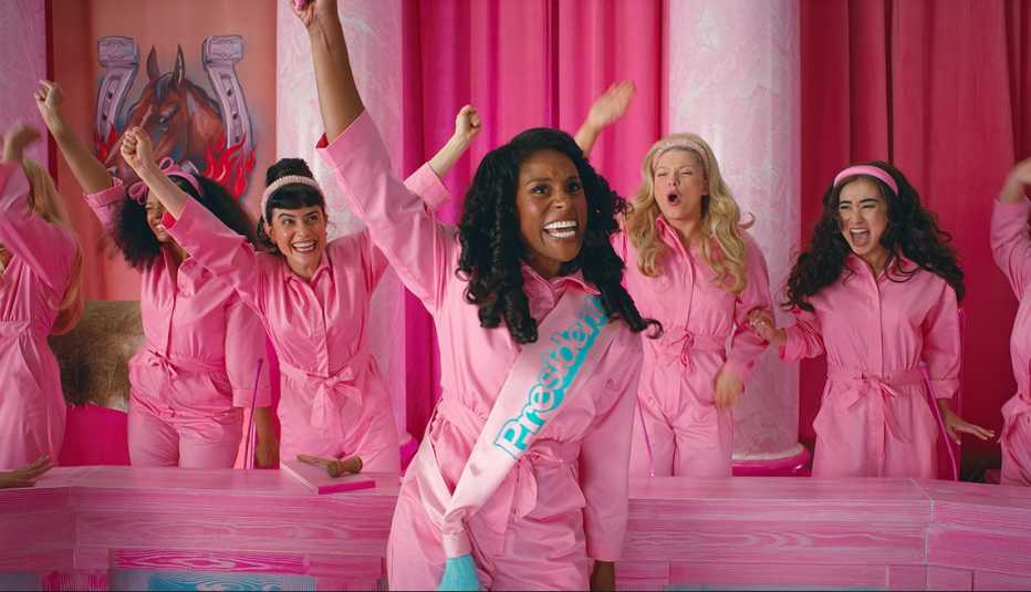 issa rae raises her arm in the air as other barbies cheer on in a scene from the film barbie