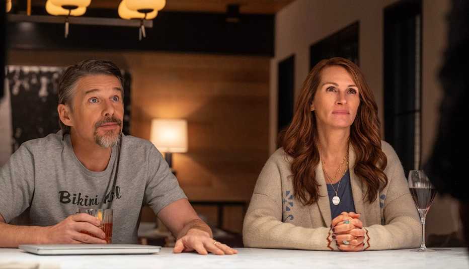 Ethan Hawke and Julia Roberts sitting at a table in The Netflix film "Leave the World Behind."