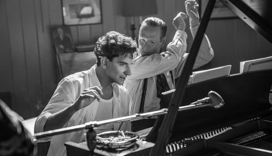 Bradley Cooper as Leonard Bernstein and Brian Klugman as Aaron Copland sitting in front of a piano in "Maestro."