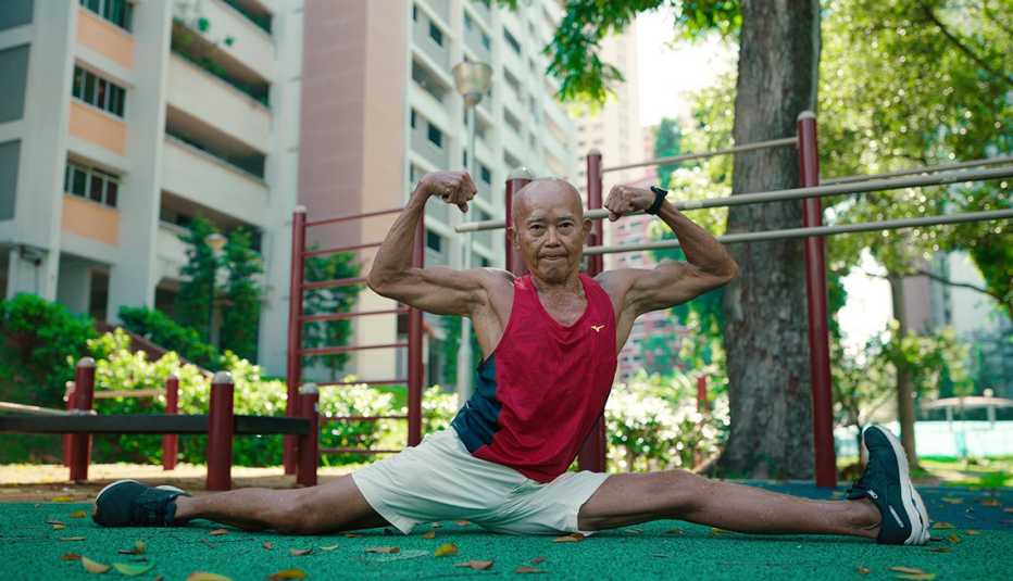 a man flexing his arms while doing the splits in the netflix documentary series live to 100 secrets of the blue zones