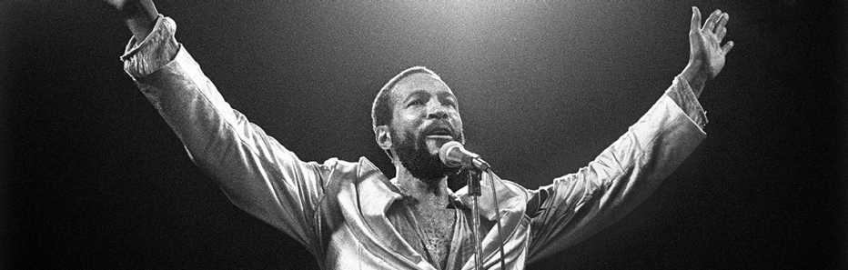 Marvin Gaye with his hands in the air singing.