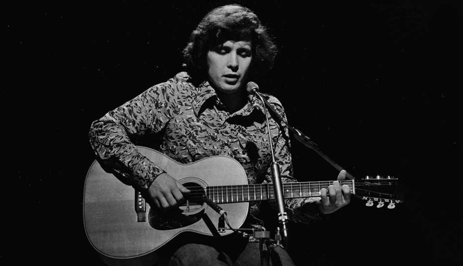 Don McLean playing his guitar during a performance in 1972