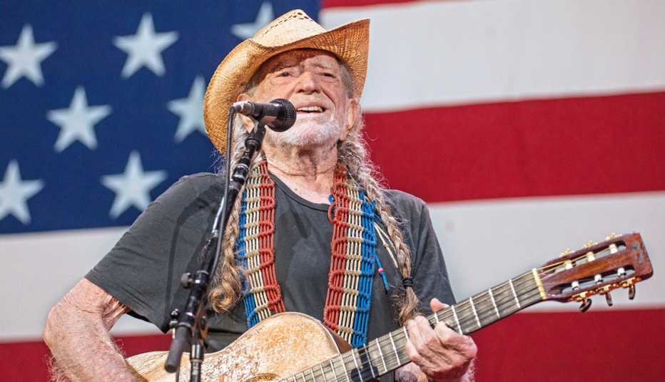 singer willie nelson on stage in front of a giant american flag