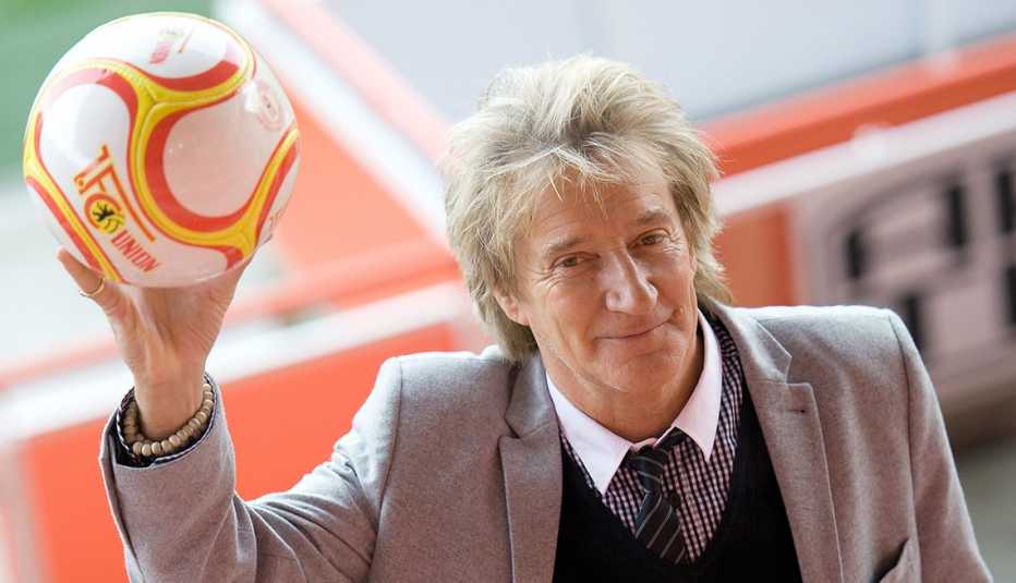 Singer Rod Stewart holding a soccer ball in his hand