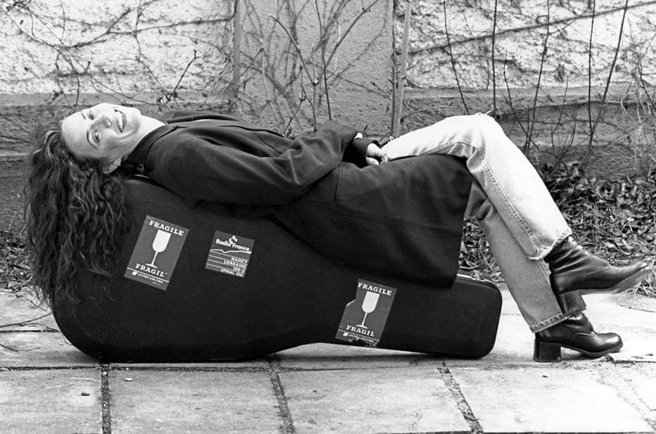 Sheryl Crow lying on guitar case, 1995