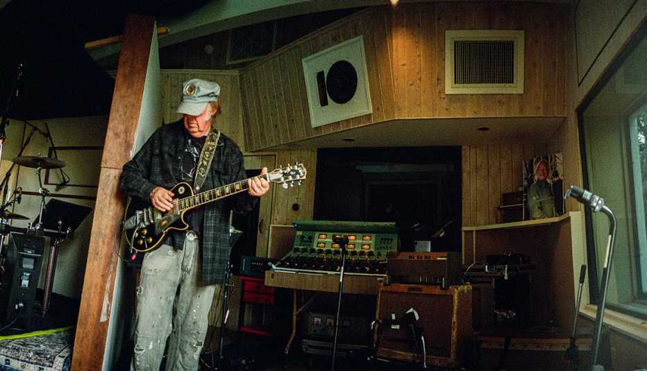 Neil Young playing a guitar in a music studio