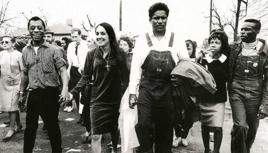 joan baez holds hands with writer james baldwin and leader james forman during a civil rights march in alabama