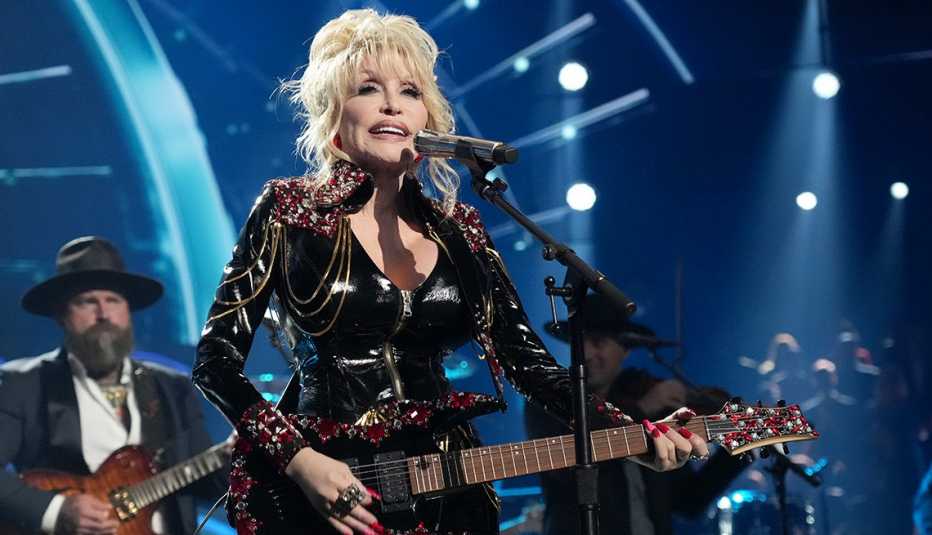 Dolly Parton performing with her guitar onstage at the 37th Annual Rock & Roll Hall of Fame Induction Ceremony