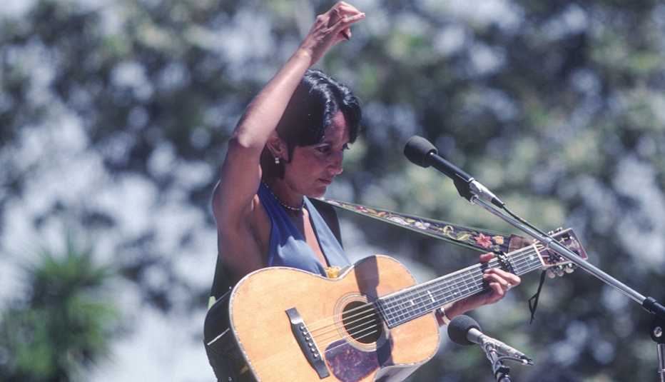 joan baez with an acoustic guitar as she performs at a concert in santa barbara
