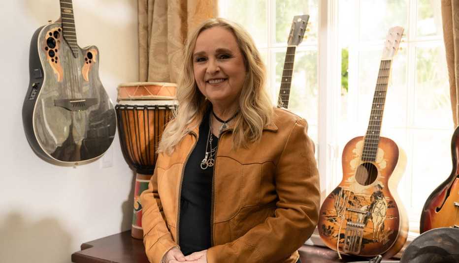 melissa etheridge smiling in a room filled with guitars