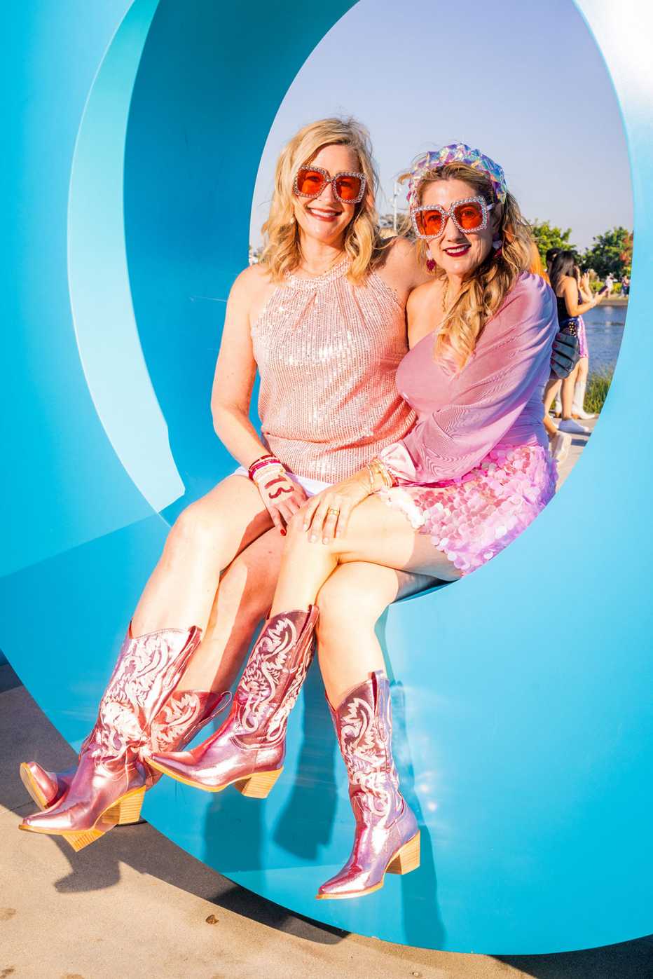 friends kathleen holtzer and keri evilsizor posing in sparkly pink outfits and metallic pink cowboy boots outside sofi stadium in los angeles california