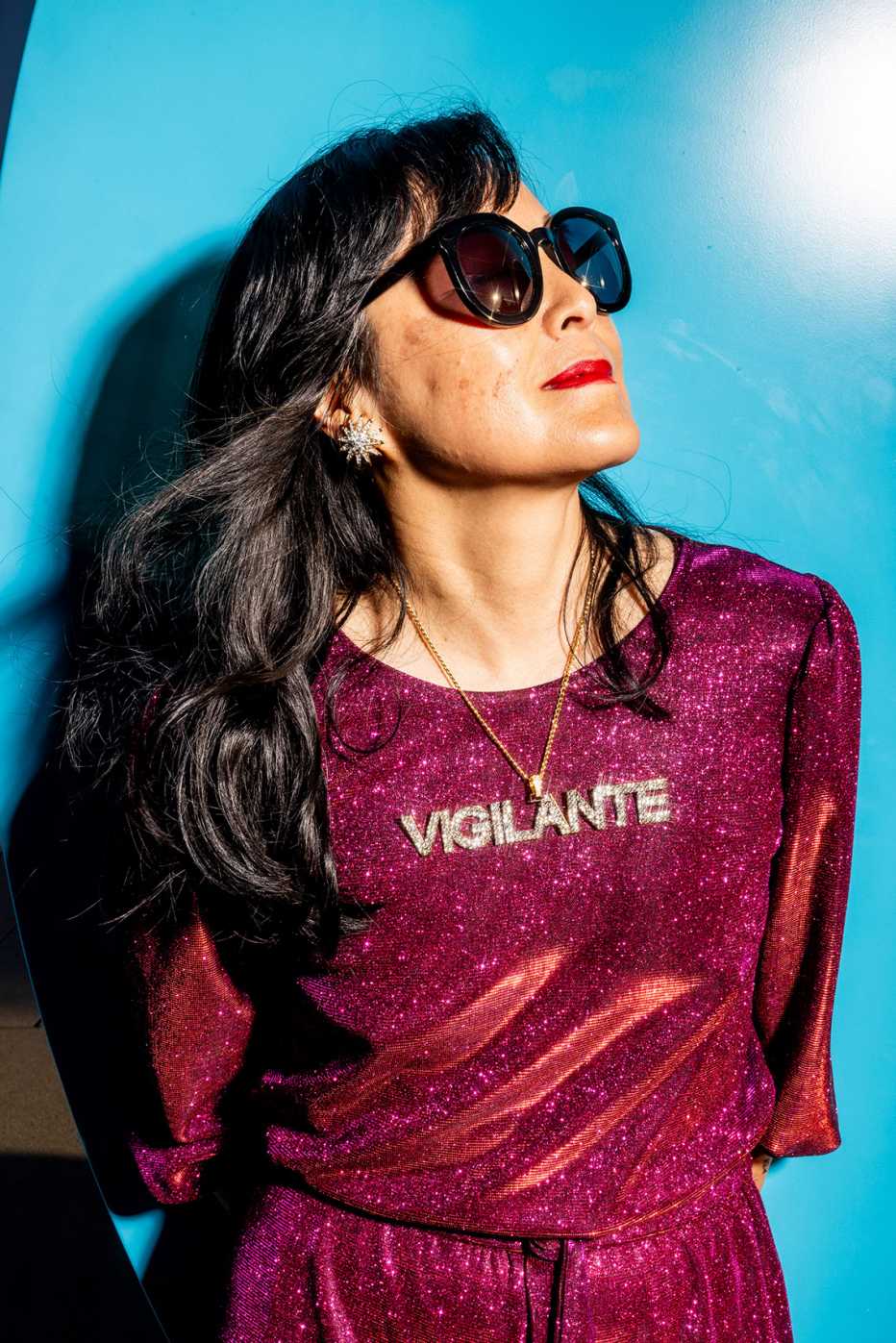 jenny ho wearing a sparkly jumpsuit and a rhinestone necklace that says vigilante