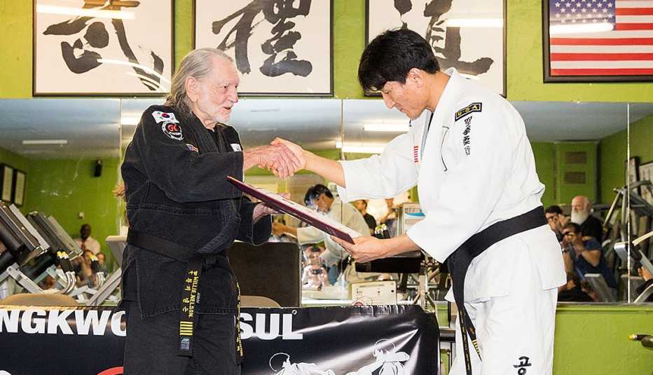Willie Nelson shakes the hand of Grand Master Sam Um as Nelson receives his 5th Degree Black Belt in the art of Gong Kwon Yu Sul at Master Martial Arts in Austin, Texas