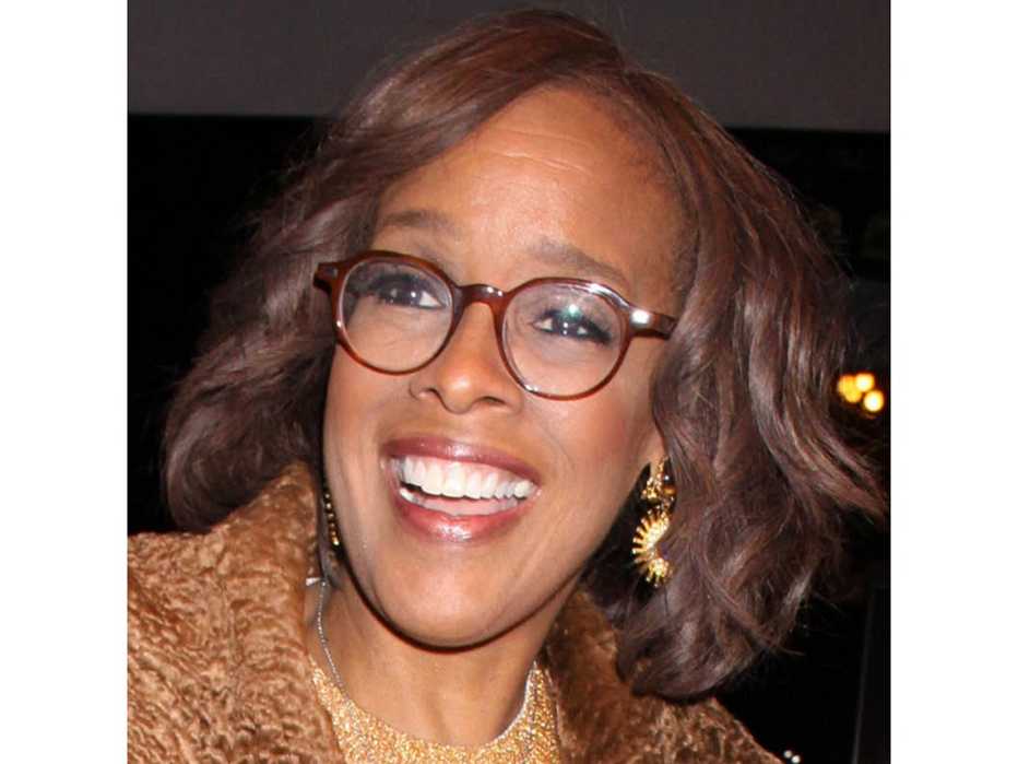 Gayle King in large thin burgundy frame glasses.