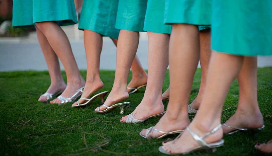 Bride's mainds dressed in green lined up while standing on grass