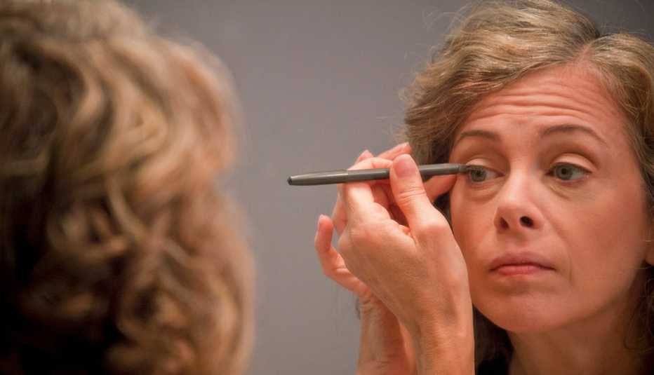 Caucasian woman applying eyeliner in mirror