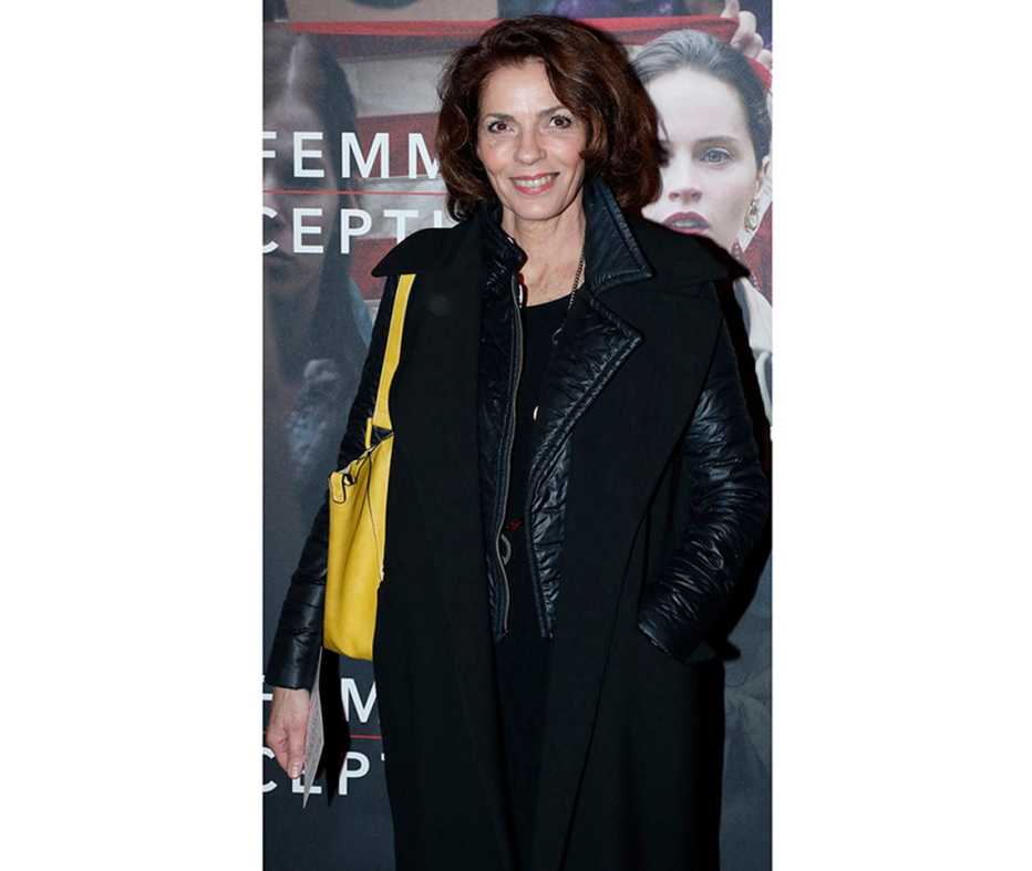 Elizabeth Bourgine wears a structured yellow shoulder bag over a black outfit