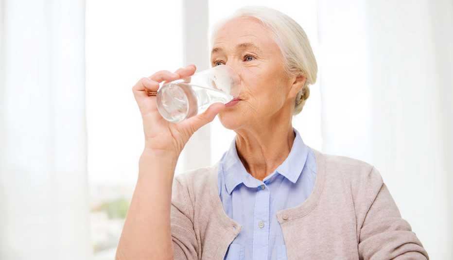 A woman drinking a glass of water at home