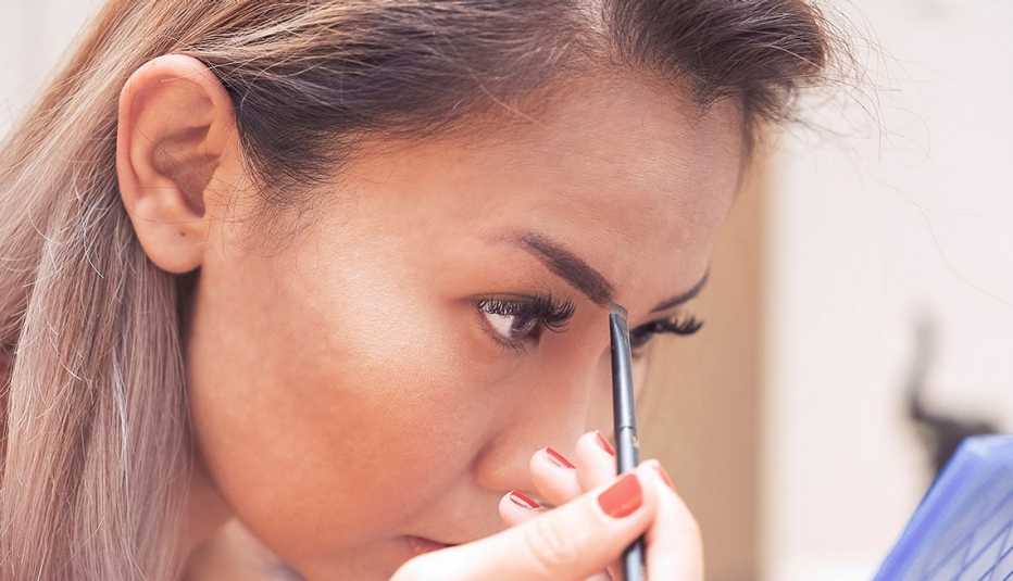A woman filling in her eyebrows with an eyebrow brush