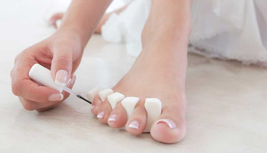 A woman applying polish to her toenails