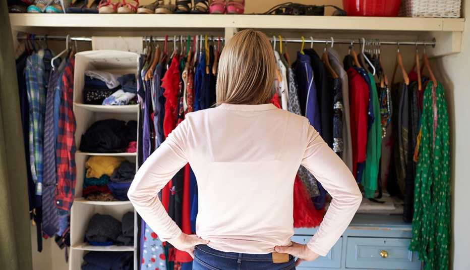 A woman in her bedroom looking at clothes and shoes in the closet