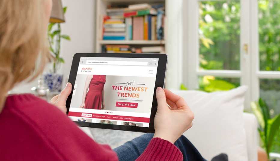 A woman sitting at home and using a tablet to shop for clothes online