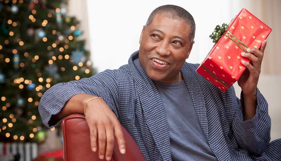 A man holding and shaking a holiday gift
