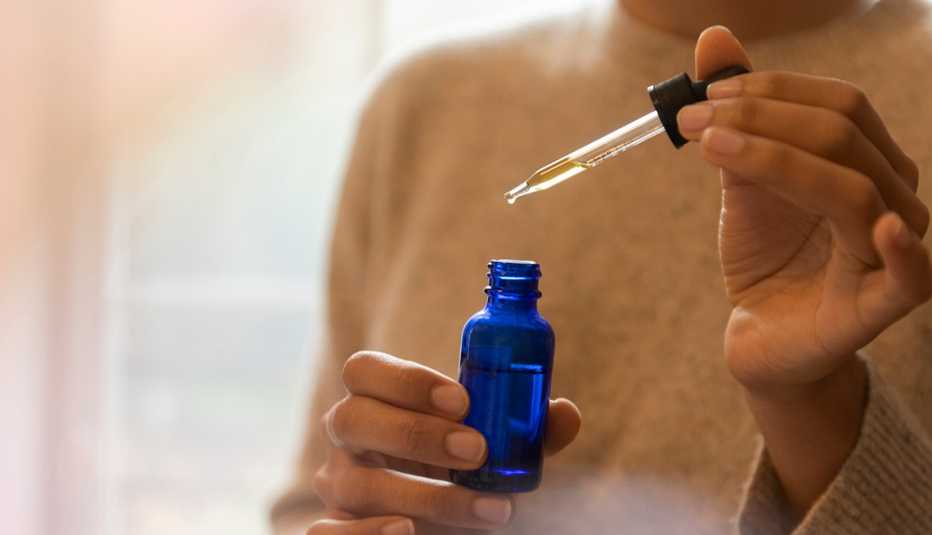 A woman holding a pipette and a bottle of aromatherapy oil