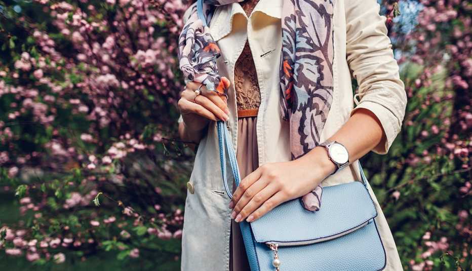 A woman holding a stylish blue handbag and wearing trendy outfit in a garden